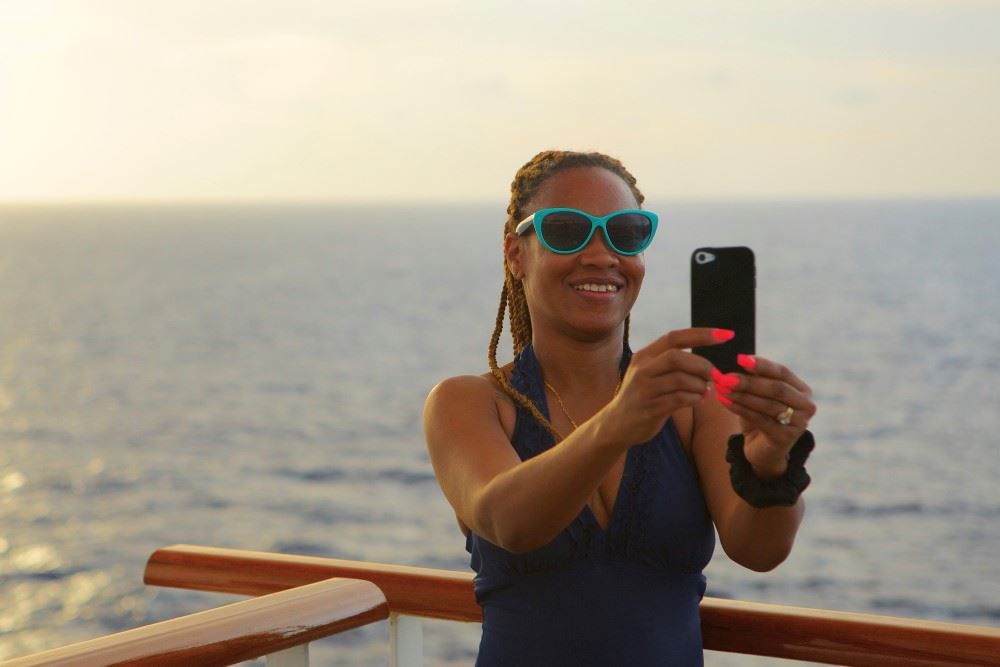 african american woman on cruise ship holding cell phone