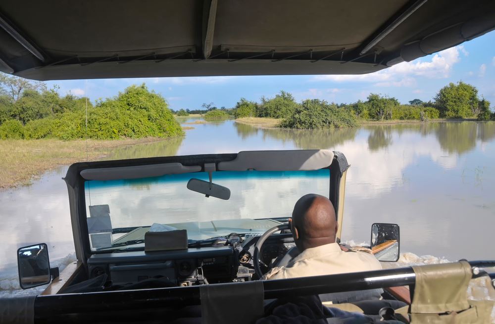 A safari vehicle driving through water in the Okavango Delta in Botswana