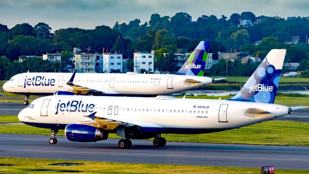 Two JetBlue Airbus airplanes taxing on a runway 