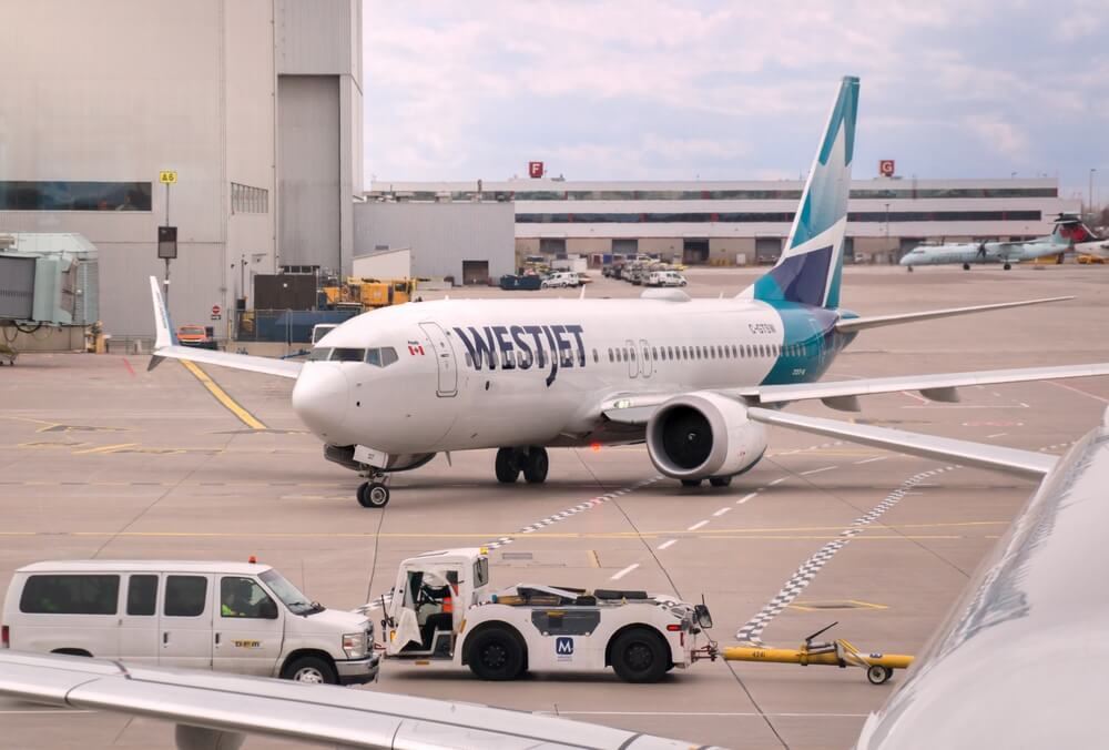 WestJet plane on runway with mechanics 