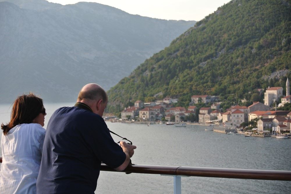 couple looking out over the railing of their luxury cruise to the mediterranan