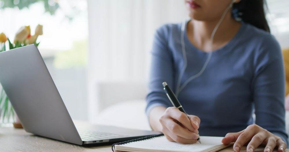 woman taking notes from something she sees on her computer artificial intelligence 