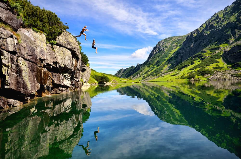 Adventure travelers jumping off cliff
