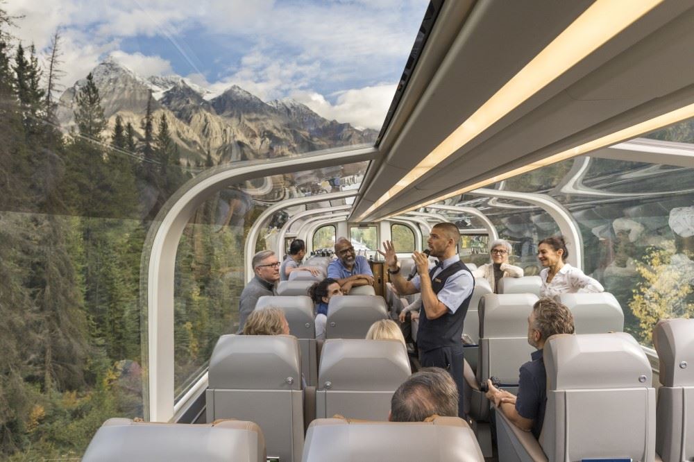 A guide talks to passengers on a Rocky Mountaineer train