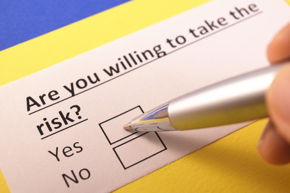 travel agent's hand holding a pen answering the question are you willing to take the risk