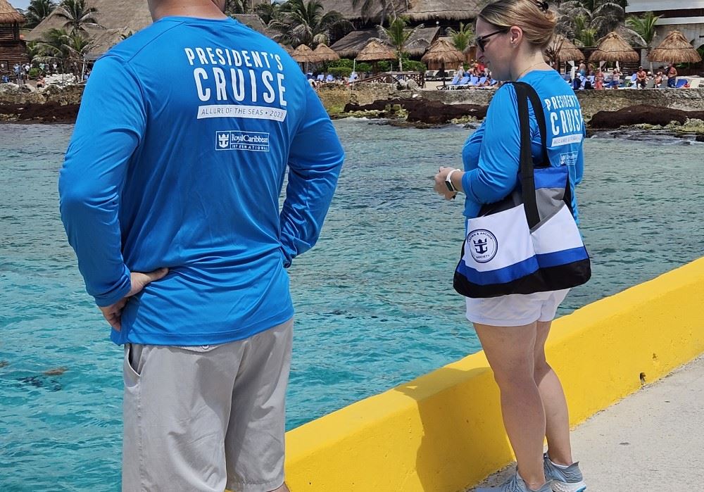 cruisers wearing royal caribbean president's cruise t-shirts standing on the costa maya pier