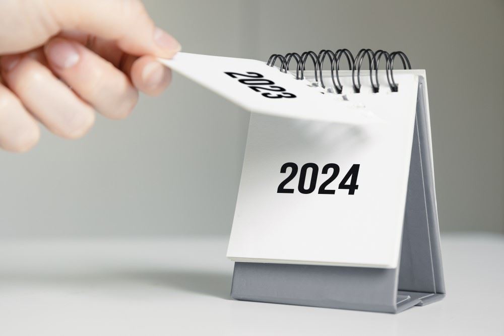 woman's hand ripping off 2023 calendar to reveal 2024