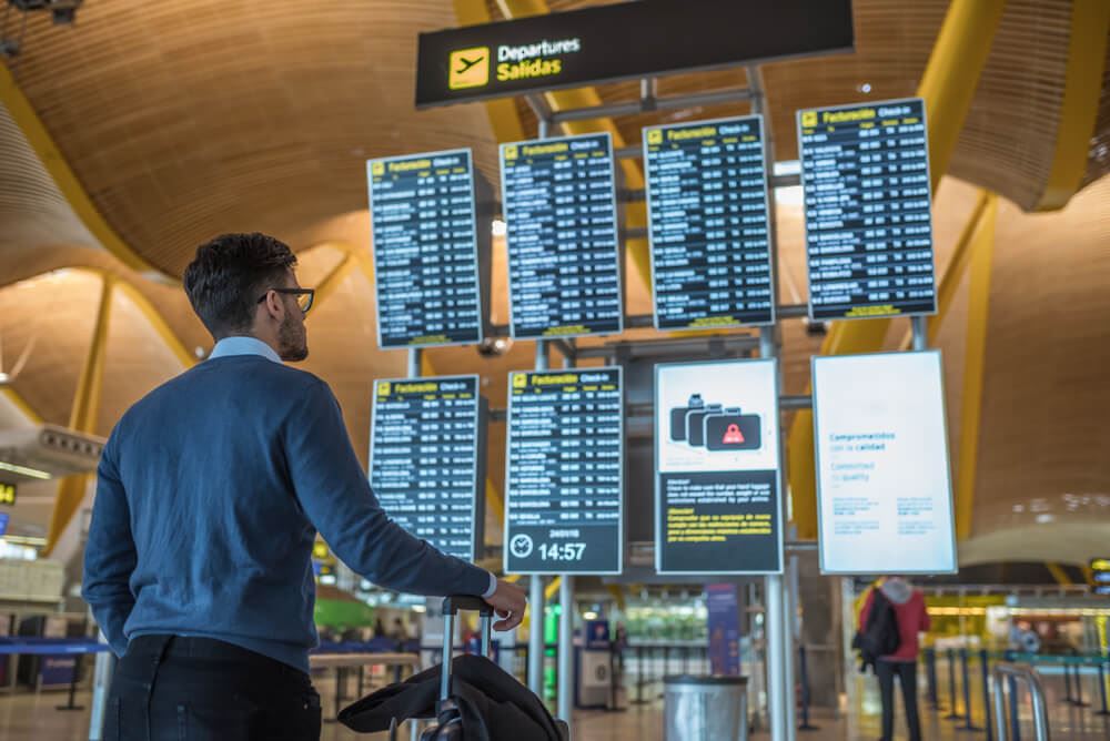Passenger looking at cancellation board at airport 