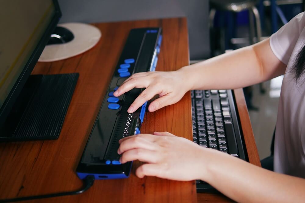 hands on a keyboard designed for someone who is visually impaired