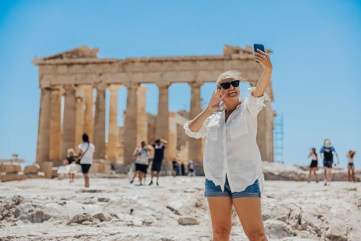 Woman traveler in greece taking a selfie in front of ruins